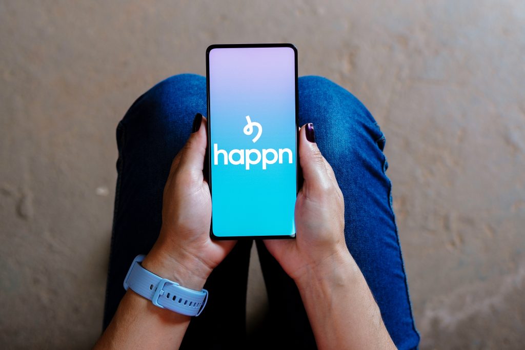 Mão segurando celular com app Happn na tela